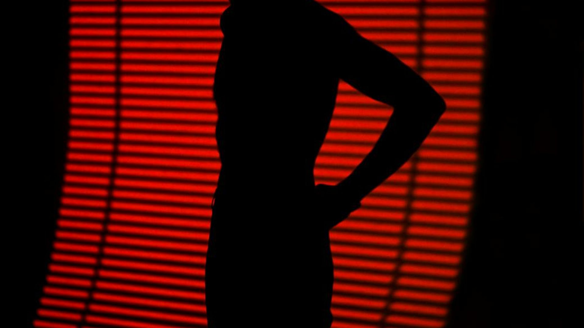 Silhouette of a person in a serene yoga pose against a dark, minimalist background.